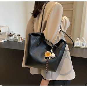 Détail d'un sac cabas en cuir noir avec charm sur le thème du sport dans un café