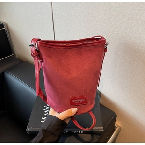 Deep burgundy frosted suede bucket bag with leather handle and slender shoulder strap