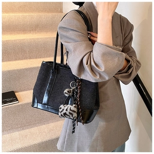 Detailed close-up of dark grey tweed tote bag with leather straps and decorative scarf