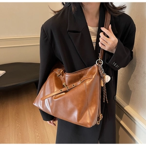 Detail of vintage brown leather tote bag featuring a metal ring buckle and soft PU texture