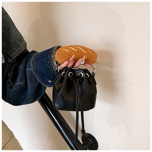 Detail of creative black bucket bag featuring brown plush baguette-style handle