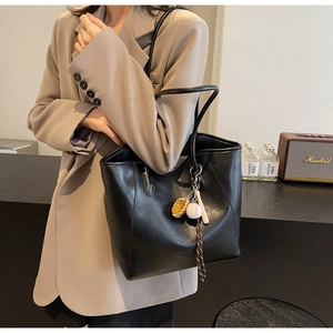 Gros plan d'un sac cabas en cuir PU noir avec pendentifs de baseball décoratifs