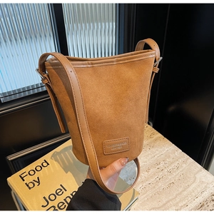 Minimalist brown suede bucket shoulder bag with adjustable strap and silver hardware accents