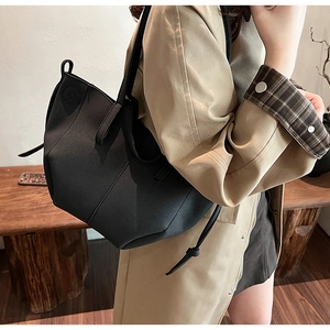 Side view of black large capacity tote bag worn by model in a cozy indoor setting