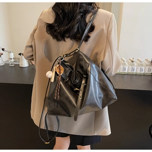 Detail of black leather tote bag with metal studs and baseball bat keychain accessory