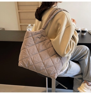 Detail view of large quilted tote bag with classic diamond stitching and wide strap