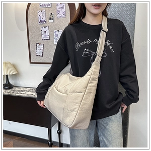 Close-up of beige nylon crossbody bag featuring an adjustable wide strap and side pockets