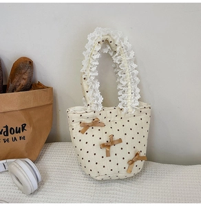 Dettaglio della borsa in cotone beige a pois marroni con rifiniture in pizzo sui manici