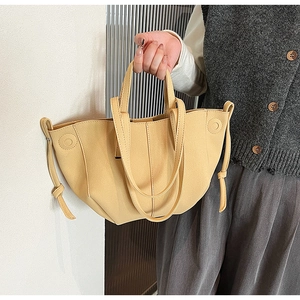 Detail of light yellow PU leather tote bag with side drawstring knot and slim handles