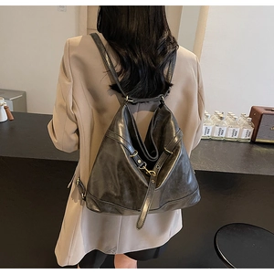Detail of dark grey soft PU leather backpack showing slouchy texture and brass hardware