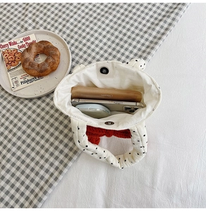 Detailed top view of white polka dot quilted tote bag with red bow and daily essentials