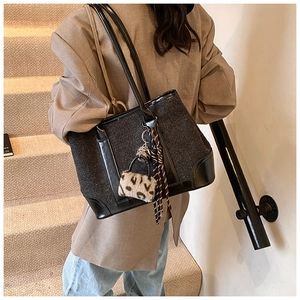 Detail of grey textured tote bag with leopard charm and geometric scarf accessory