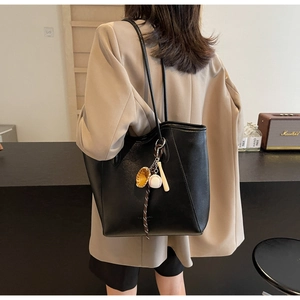 Détail d'un grand sac cabas noir en similicuir PU avec un pendentif sur le thème du baseball