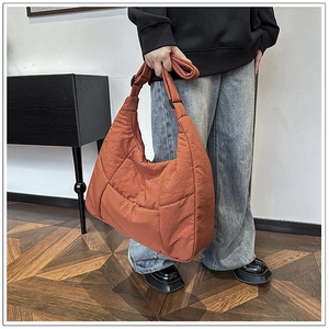 Detail of burnt orange quilted nylon hobo bag with wide adjustable shoulder strap