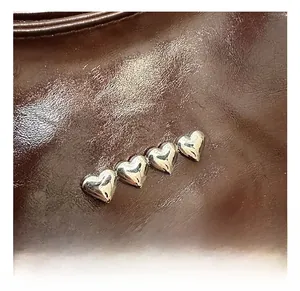 Dettaglio macro di borchie in metallo a cuore argento sulla borsa in pelle cerata