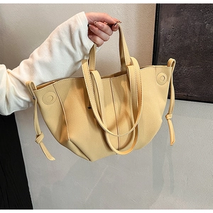 Detail of trendy beige PU tote bag featuring decorative drawstring knots on both sides