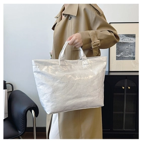 Close-up of silver metallic Tyvek tote bag with embossed text and dual handles