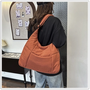 Detail of a large orange quilted nylon tote bag showing its texture and water-resistant fabric