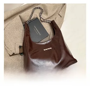 Dettaglio borsa tote in pelle PU lucida marrone scuro con borchie a cuore argentate