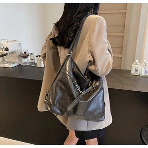 Close-up of black vintage PU leather shoulder bag with gold buckles in a cafe setting