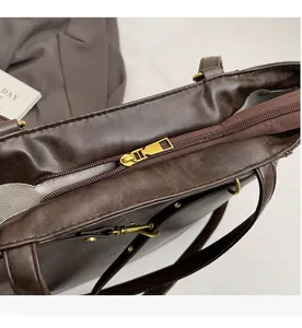 Detail view of a smooth bronze zipper closure on a vintage dark brown leather tote bag