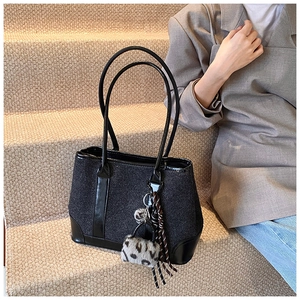 Detail of dark grey tweed tote bag with leather trim and leopard plush charm