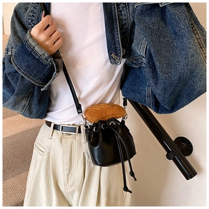 Detail of black PU leather bucket bag featuring a unique croissant plush charm and silver hardware