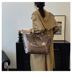 Detailed view of deep brown crinkled tote bag with glossy finish and white text
