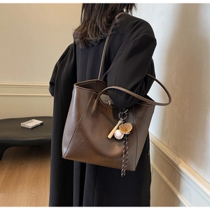 Détail du sac cabas en cuir marron foncé avec un pendentif décoratif thème baseball