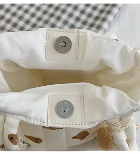 Gros plan du fermoir magnétique sur un sac en coton blanc avec bordure en dentelle fine