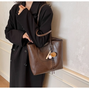 Détail d'un sac cabas en cuir PU marron foncé avec un charmant pendentif de baseball