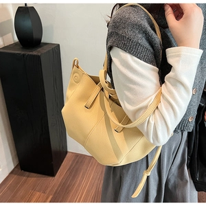 Detail view of bright yellow faux leather tote bag with pebble texture and wide straps
