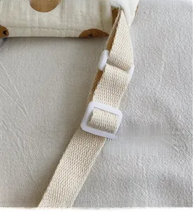 Dettaglio della tracolla tessuta regolabile con fibbia in plastica bianca su borsa cotone