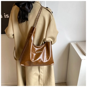 Dettaglio della borsa tote in pelle PU marrone con cuori metallici e tracolla a catena