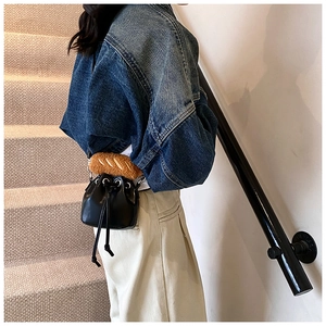 Detail of black PU leather bucket bag featuring a unique croissant shaped plush handle