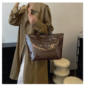 Detail view of brown DuPont paper tote bag with white text carried by a model in a coat