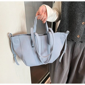 Detail view of light blue PU leather handbag with decorative drawstring and shoulder straps