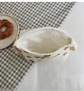 Vista interna della borsa a tracolla in tela di cotone bianco crema con orso marrone