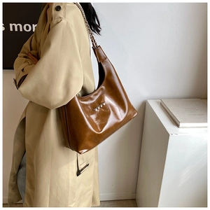 Dettaglio borsa a spalla in pelle PU marrone con cuori metallici e tracolla a catena