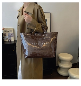 Detail of a brown glossy Tyvek tote bag featuring a crinkled texture and TOTE BAG print