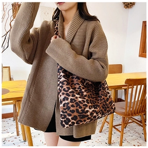 Close-up of leopard print canvas tote bag with brown chunky knit cardigan details