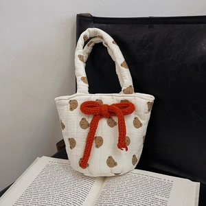 Quilted cotton shoulder bag with bear patterns and a red bow on a vintage book
