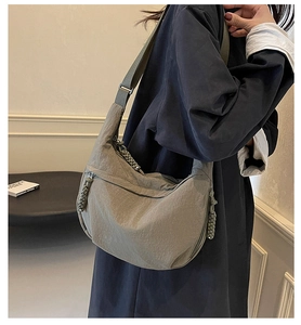 Detail view of khaki nylon dumpling bag with woven zipper pulls and adjustable strap