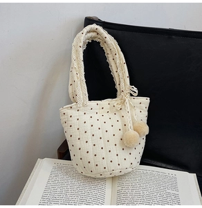 Détail d'un sac cabas en coton matelassé à pois avec dentelle et pompons en peluche
