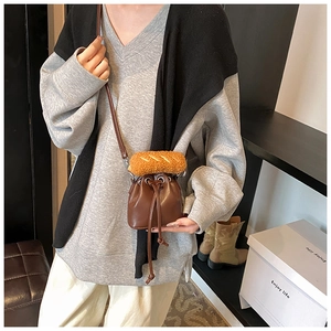 Detail of a mini bucket bag featuring a plush faux baguette charm and drawstring closure