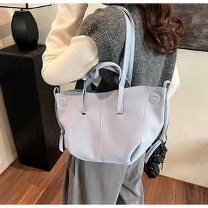 Detail of a light blue faux suede tote bag with decorative side ties and shoulder strap
