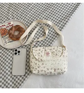 Dettaglio borsa trapuntata in cotone a fiori con etichetta tessuta e tracolla in tela
