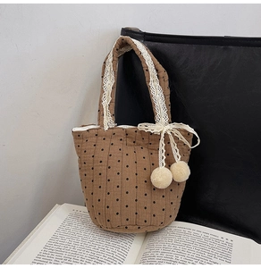 Détail d'un sac en coton matelassé marron avec pois noirs et dentelle blanche sur la poignée