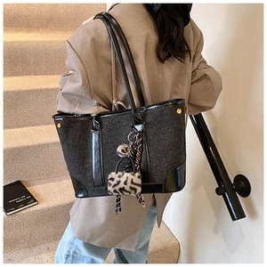 Fashionable black woven tote bag with smooth leather trim and leopard print charm