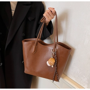 Grand sac cabas en similicuir marron avec pendentif baseball porté par un mannequin